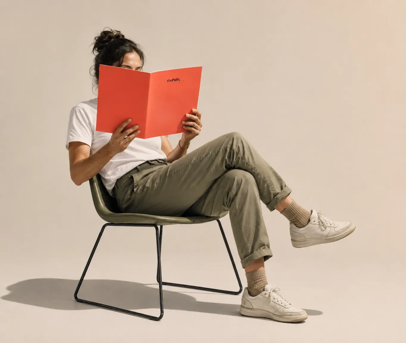 A person seated in a chair, reading a coral thePath booklet.