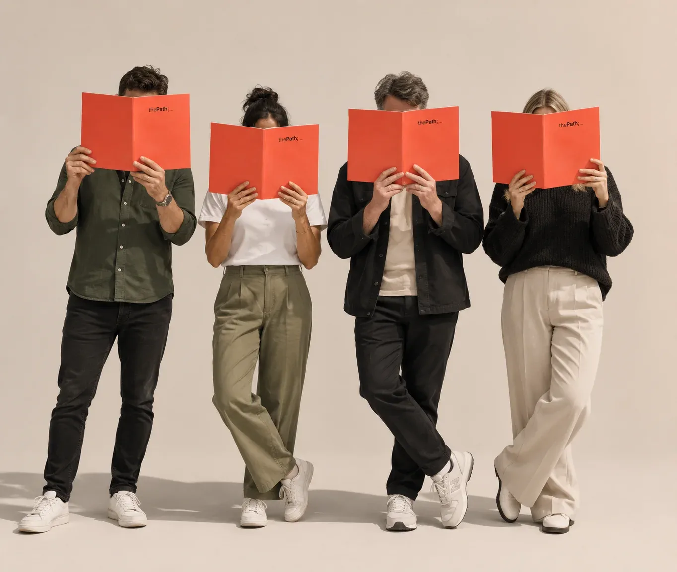 Four people standing in a row, each holding an open coral thePath booklet in front of their face.